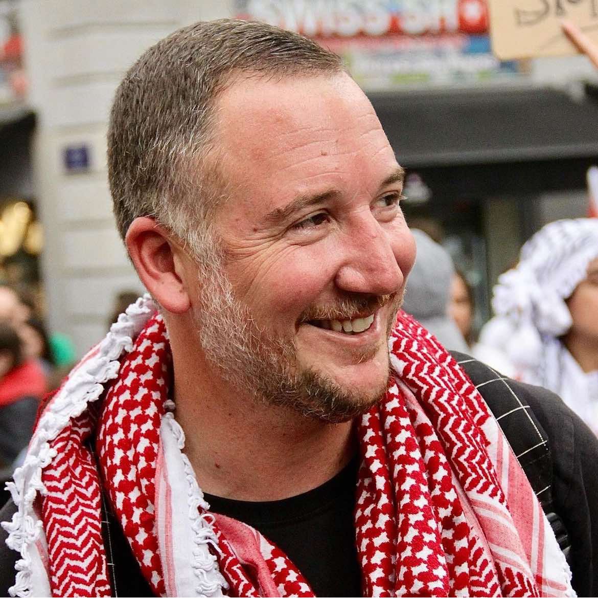 Photo of a man wearing a red scarf in a street