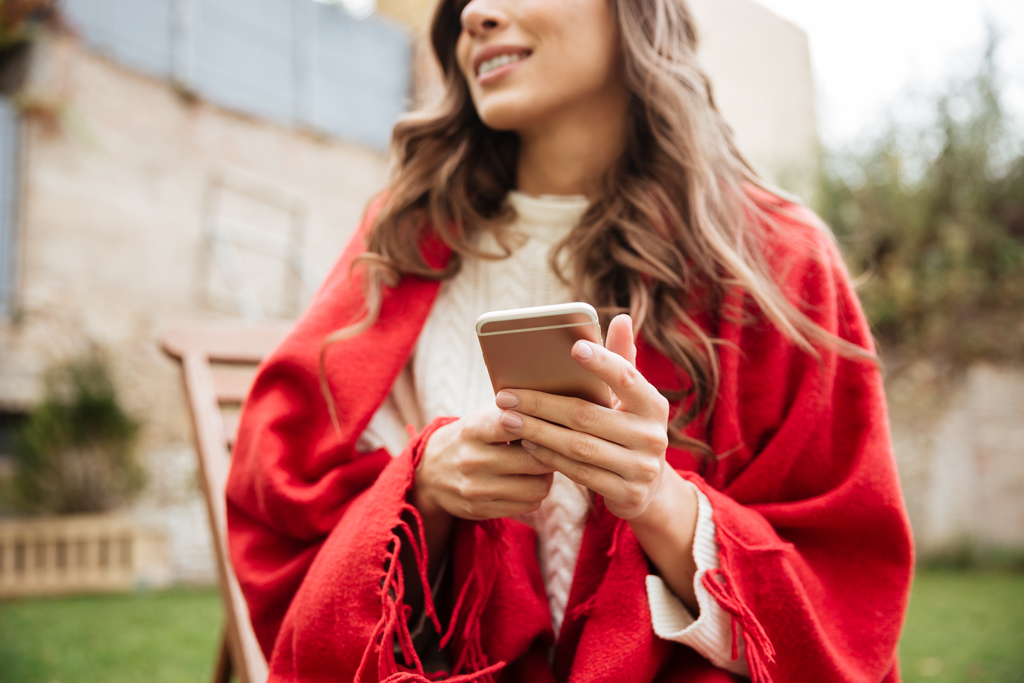 Image of a female with holding a phone and wearing a red shawl