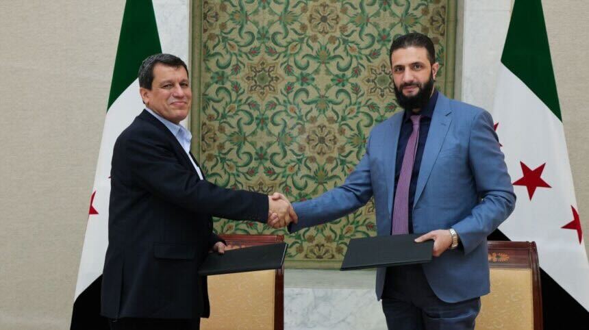 Picture of Mazloum Abdi and Sharaa shaking hands